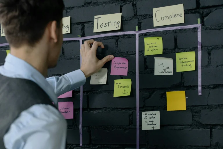 Man organizing project tasks on a wall using sticky notes in a modern office representing kanban workflow
